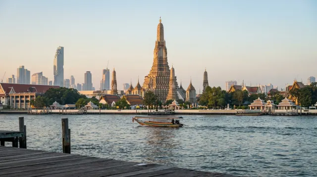 Wat Arun on the Chao Phraya at dawn with Bangkok’s riverfront beyond